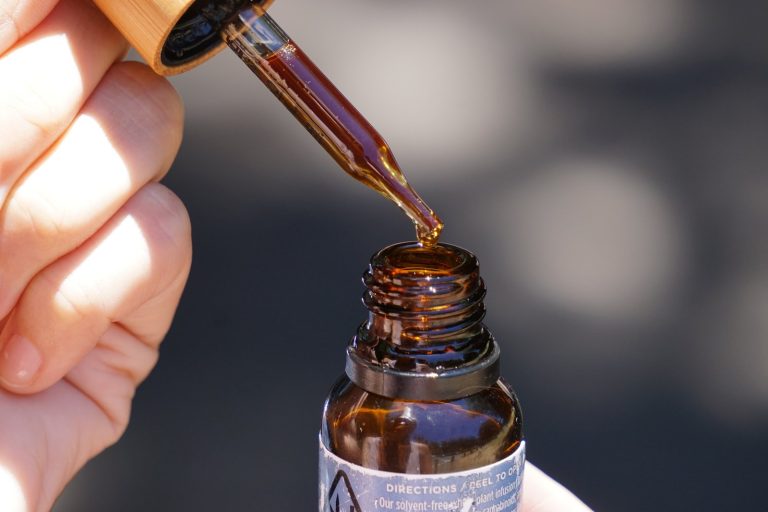 Flacon compte-gouttes d'huile de cannabis posé sur des feuilles de chanvre — illustration médicaments à base de cannabis pour la douleur neuropathique