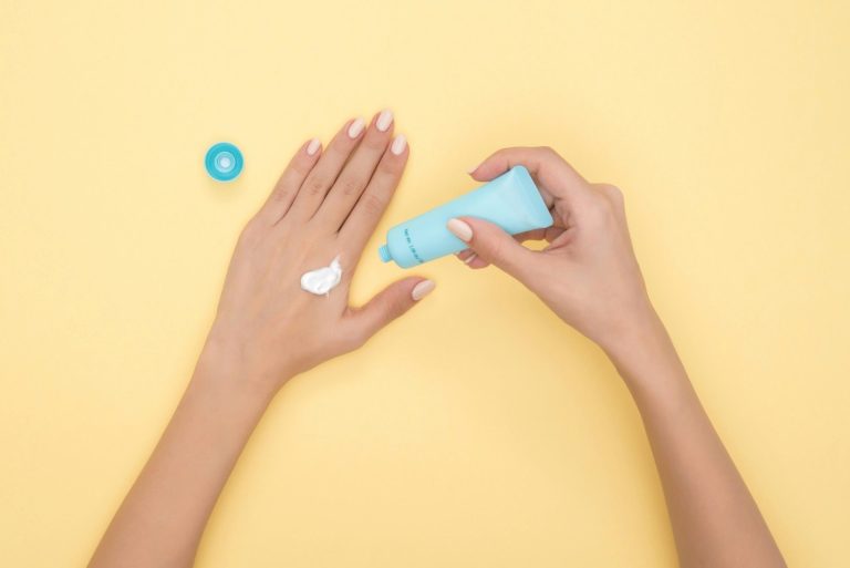 Femme appliquant une crème cosmétique sur le dos de sa main — illustration des soins topiques au CBD